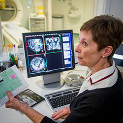 Lady Radiographer sitting at a computer screen with scanner in background